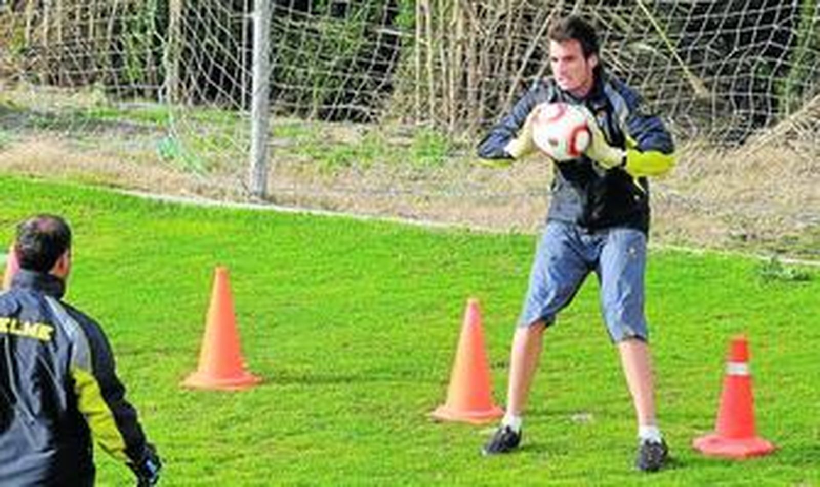 Álvaro Campos bloca un balón mientras se ejercita a las órdenes del preparador de porteros en las instalaciones de El Rosal.