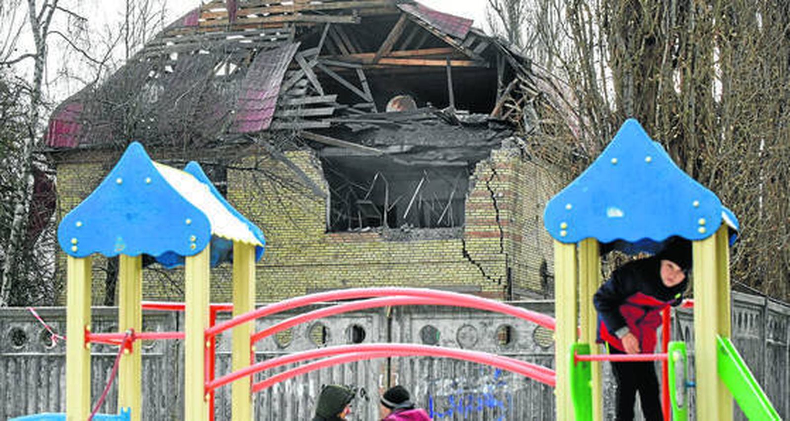 Unos niños juegan en un parque junto a un edificio atacado por Rusia en Kiev.