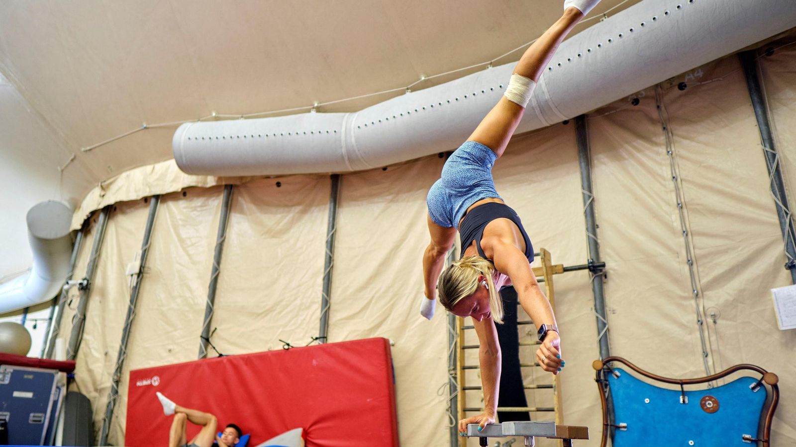Una acróbata realiza un ejercicio de equilibrio sobre manos y contorsión. 