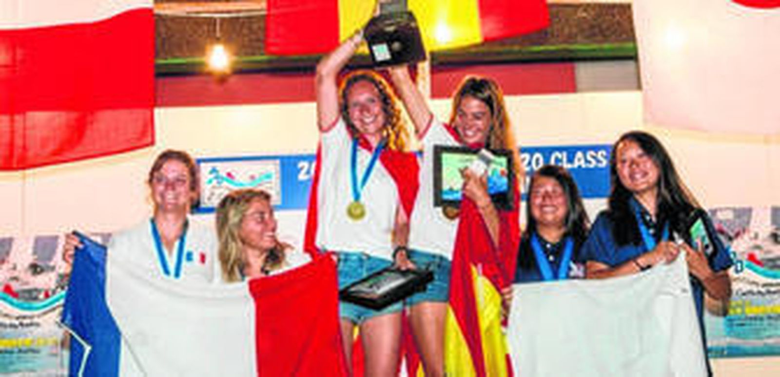 La pareja española formada por María Jesús Dávila (i) y Marta Garrido celebra su victoria en lo más alto del podio, con el dúo francés, segundo, a su izquierda, y las japonesas, bronce, a la derecha.