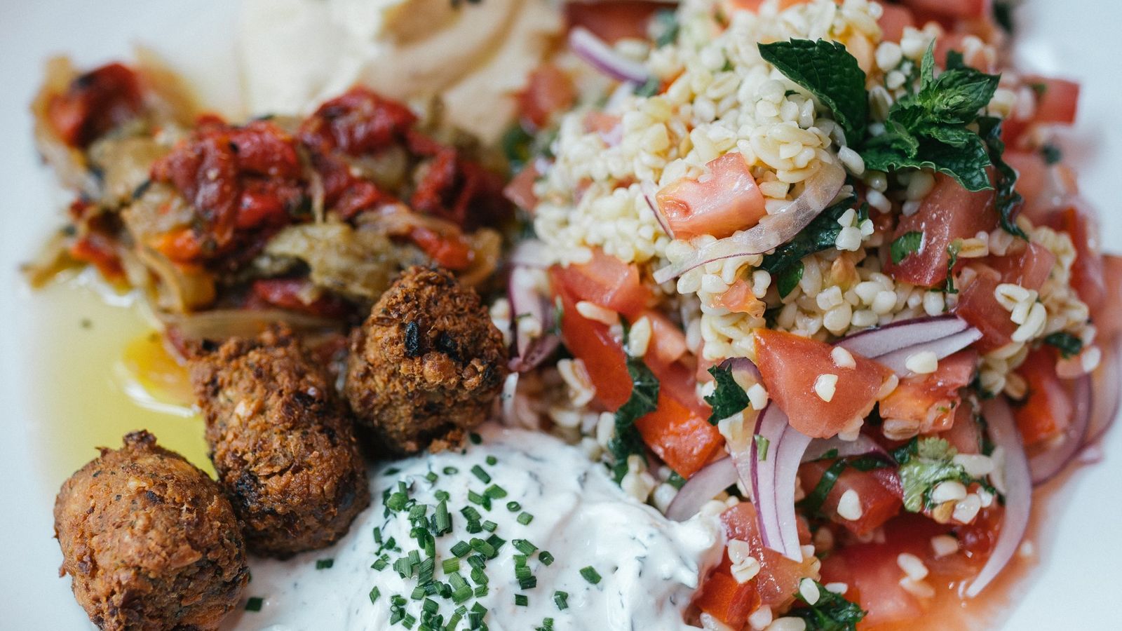 Tabulé de bulgur, humus, verduras escalibadas, salsa yogurt, falafel y pan pita.