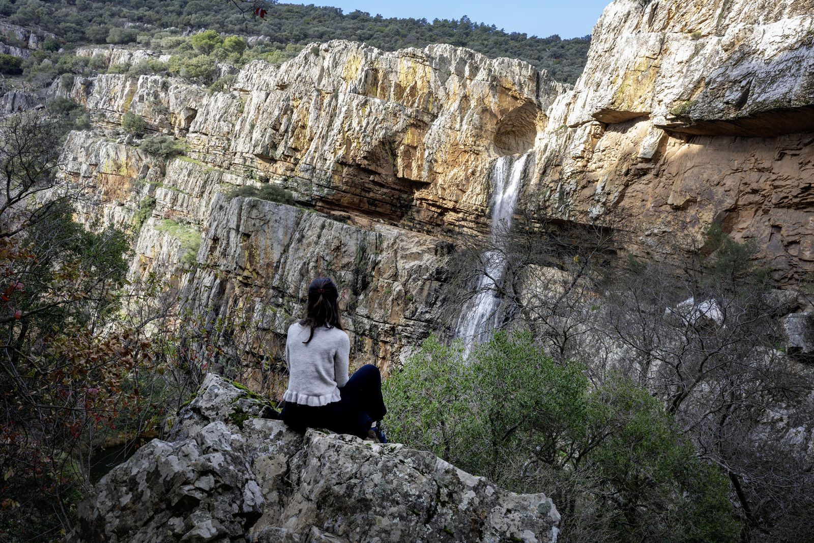 na persona observa el Salto de la Cimbarra en Aldeaquemada, con agua tras las recientes lluvias.