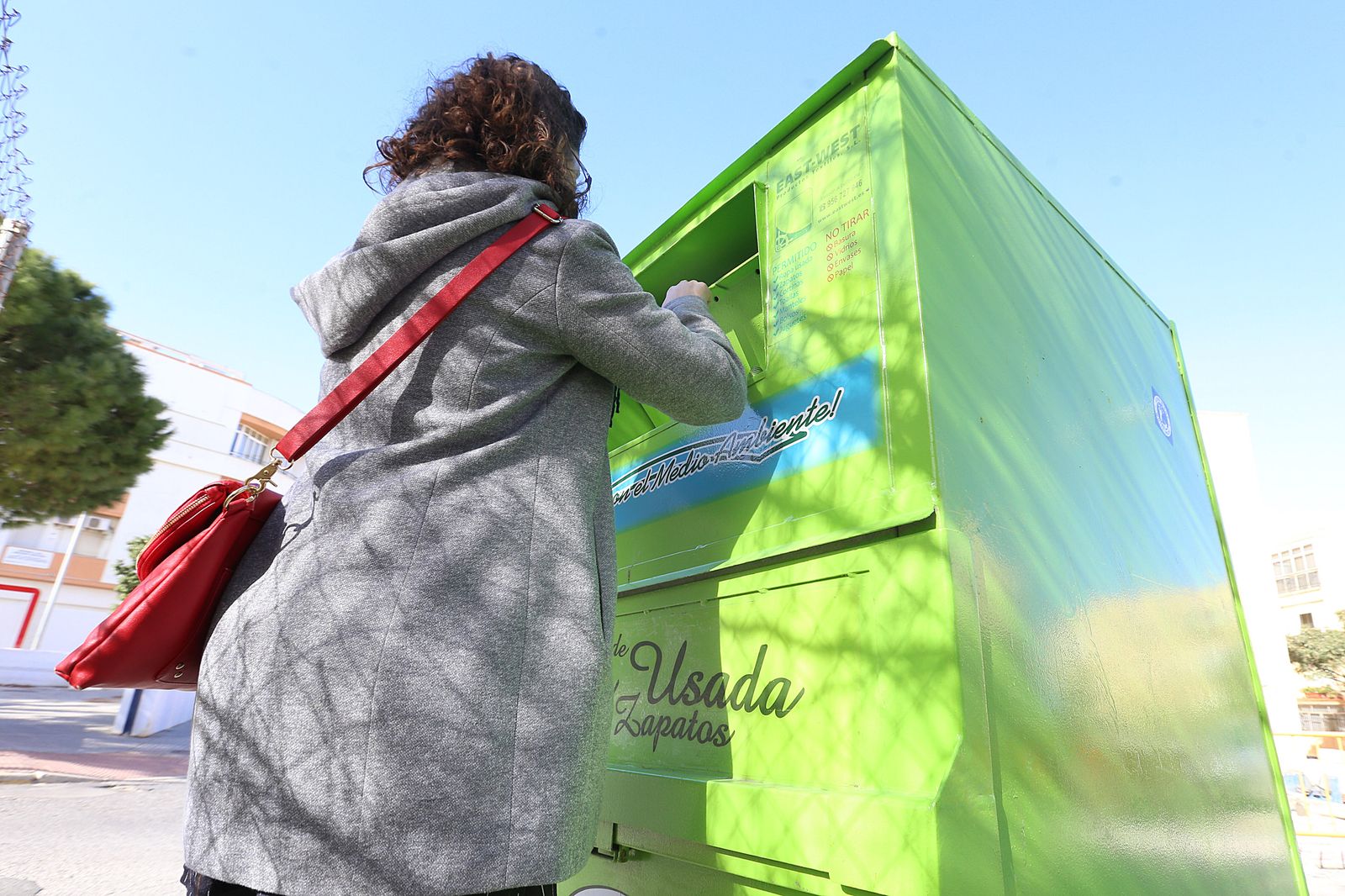 Una mujer deposita prendas en uno de los contenedores de ropa usada.