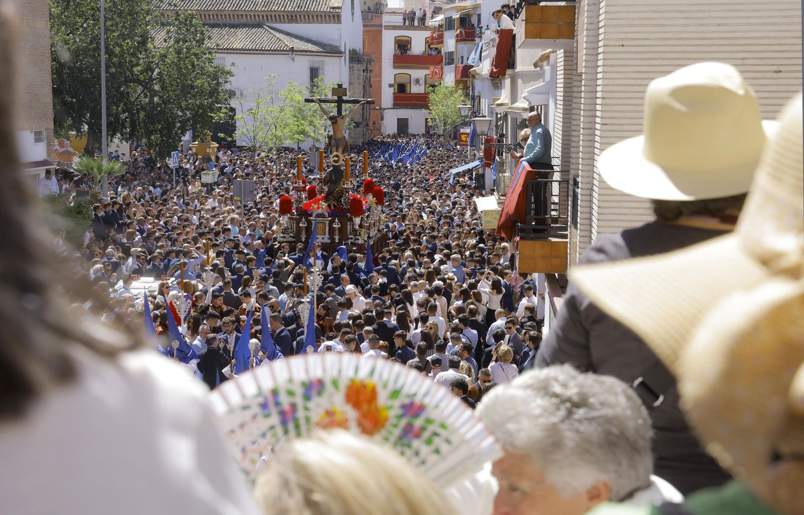 Abanicos para protegerse del sol en la salida de la cofradía de la Hiniesta en 2023.