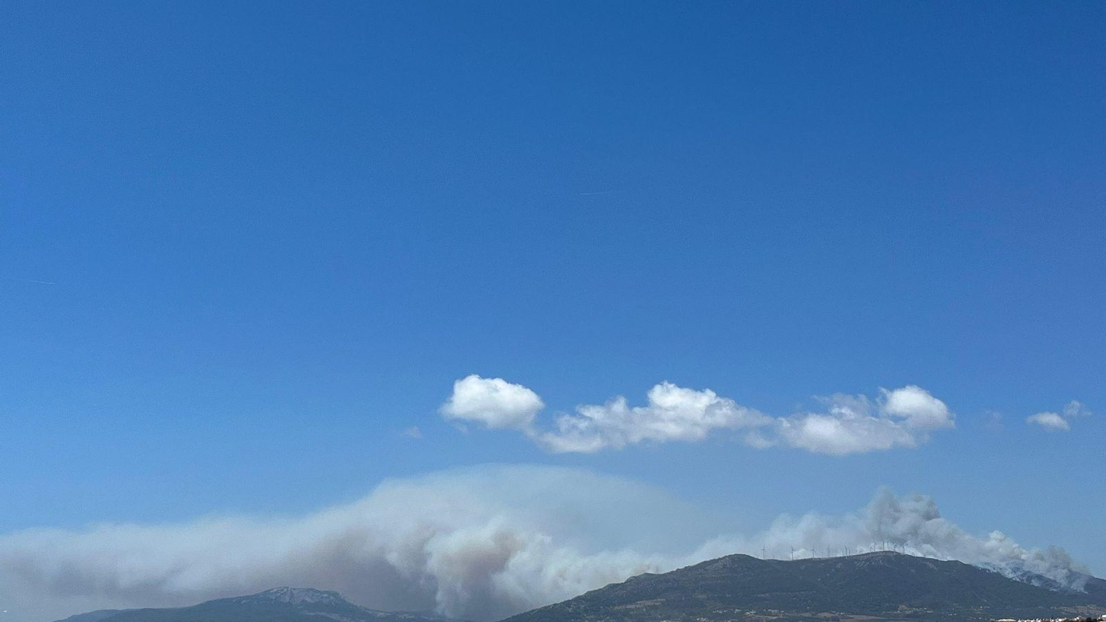 El humo del incendio, visible desde la playa de Valdevaqueros.