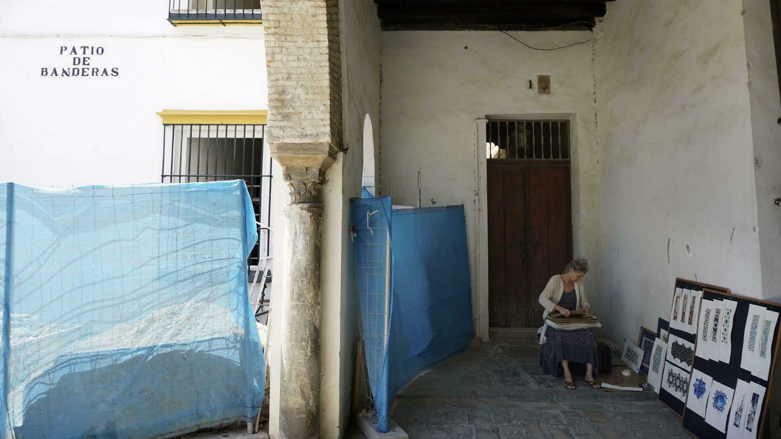 Una mujer pinta grabados en la puerta de la finca, junto al arco de entrada a la plaza.