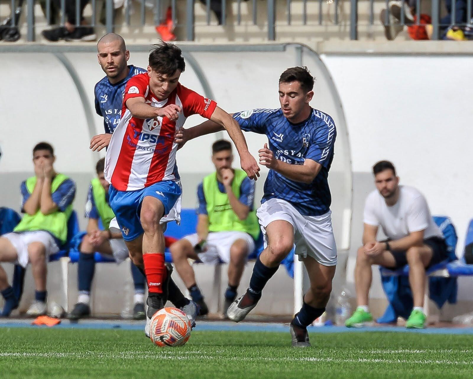 Un jugador del conjunto rojiblanco conduce el balón ante la presión de dos rivales.