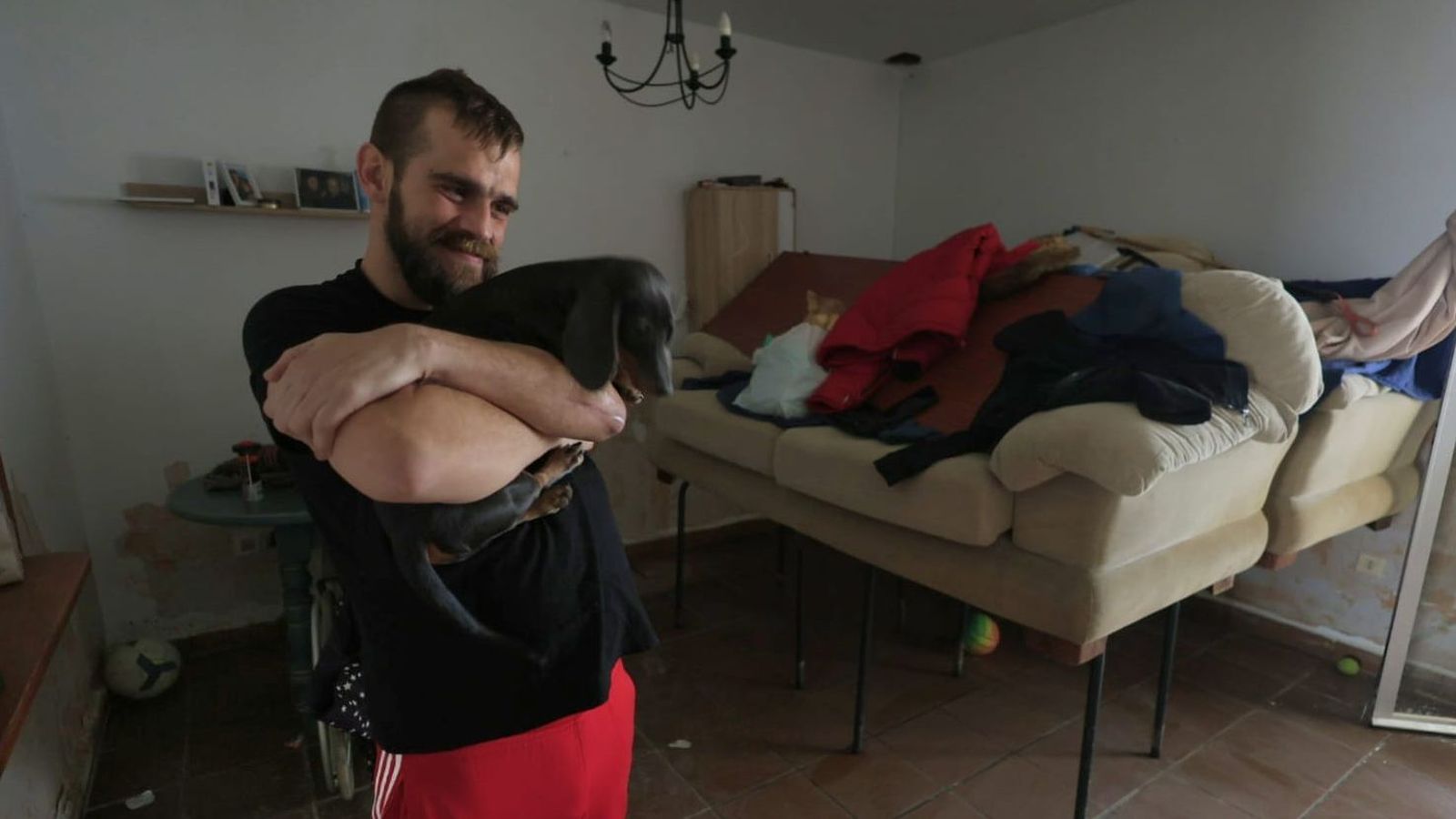 Un vecino de Tesorillo, con su perro en brazos y el sofá en alto dentro de su casa, este sábado.