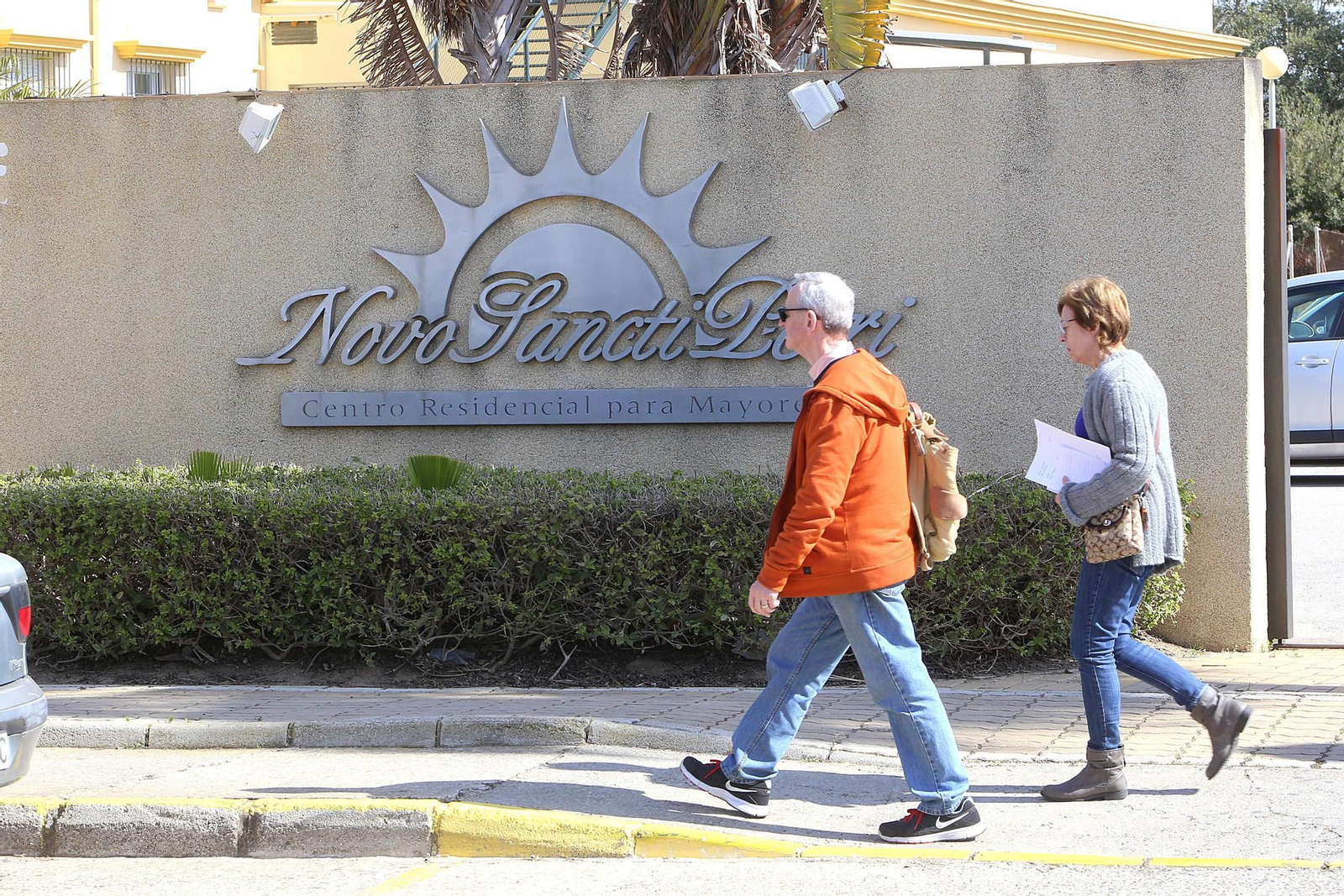 Dos personas pasan junto al logotipo de la residencia en la que estaba ingresada la mujer cuya muerte investiga el Juzgado.