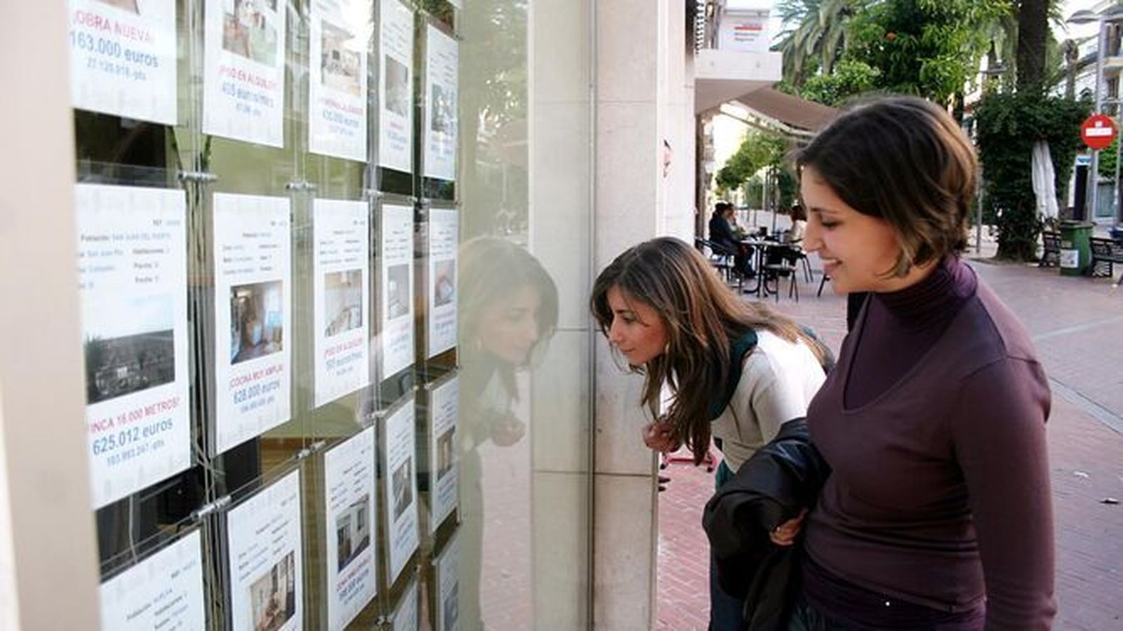 Dos jóvenes miran el escaparate de una agencia inmobiliaria