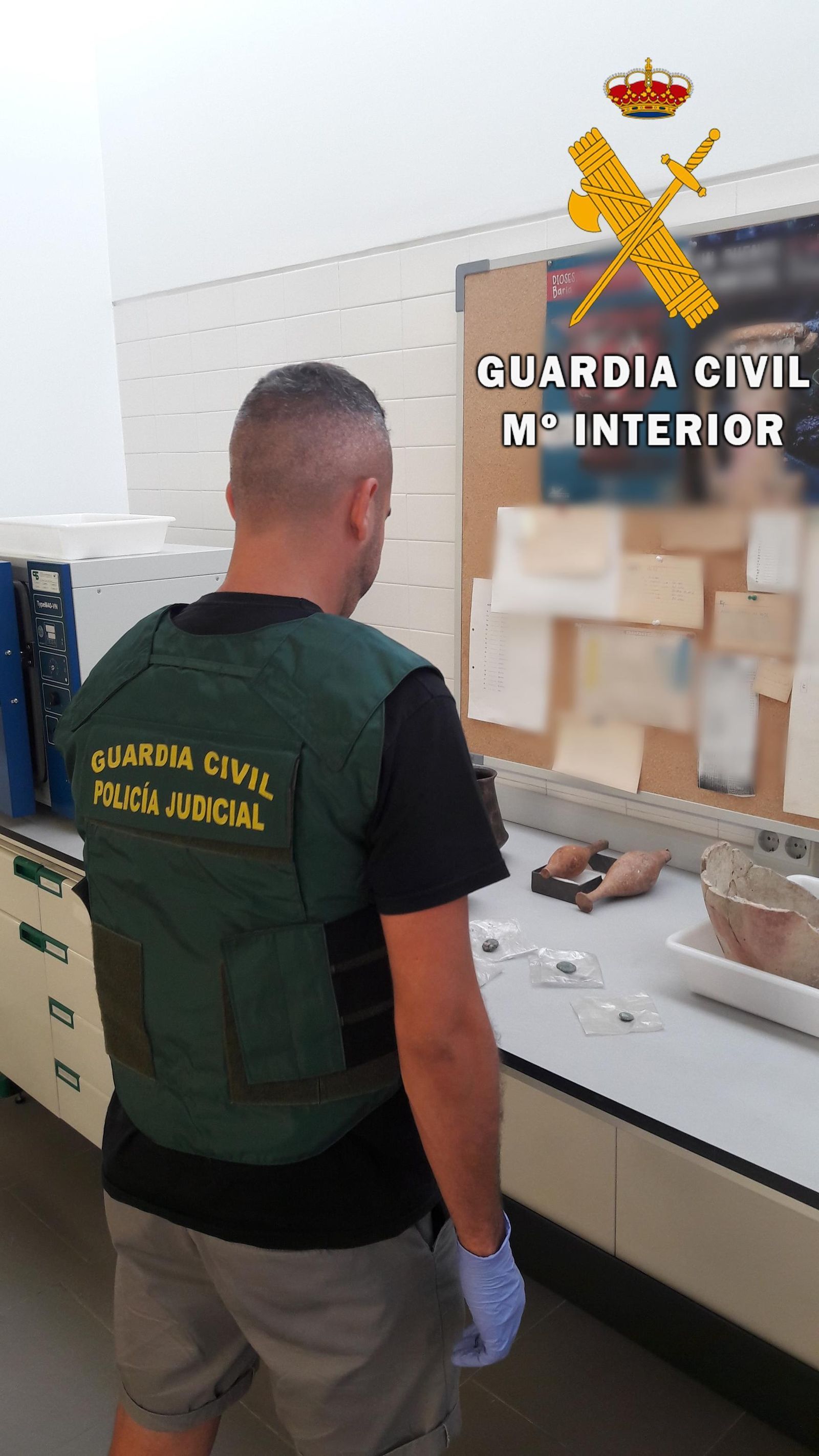 Un agente de la Guardia Civil examina el material intervenido al vendedor.