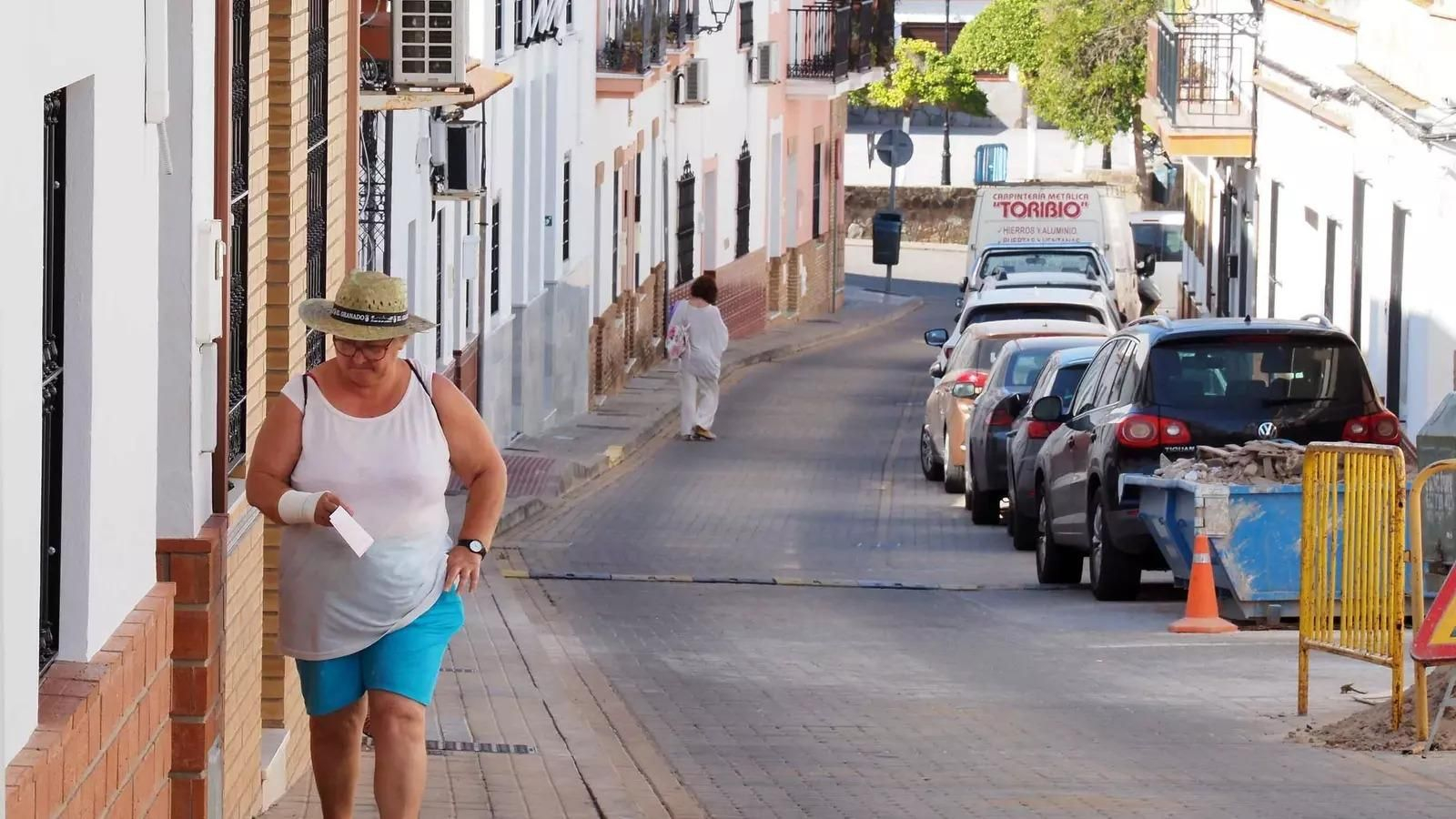 Una mujer, con sombrero, camina por una de las calles principales de El Granado.