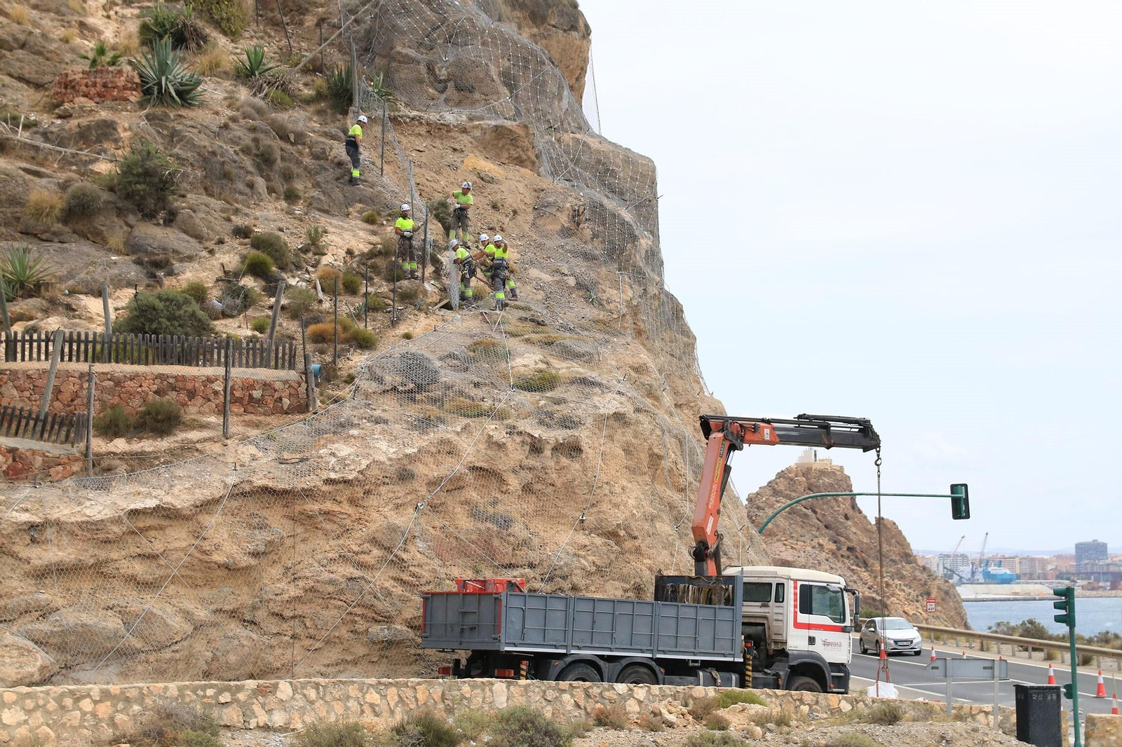 Operarios reponen la malla de sujeción tras la retirada del muro y piedras sueltas