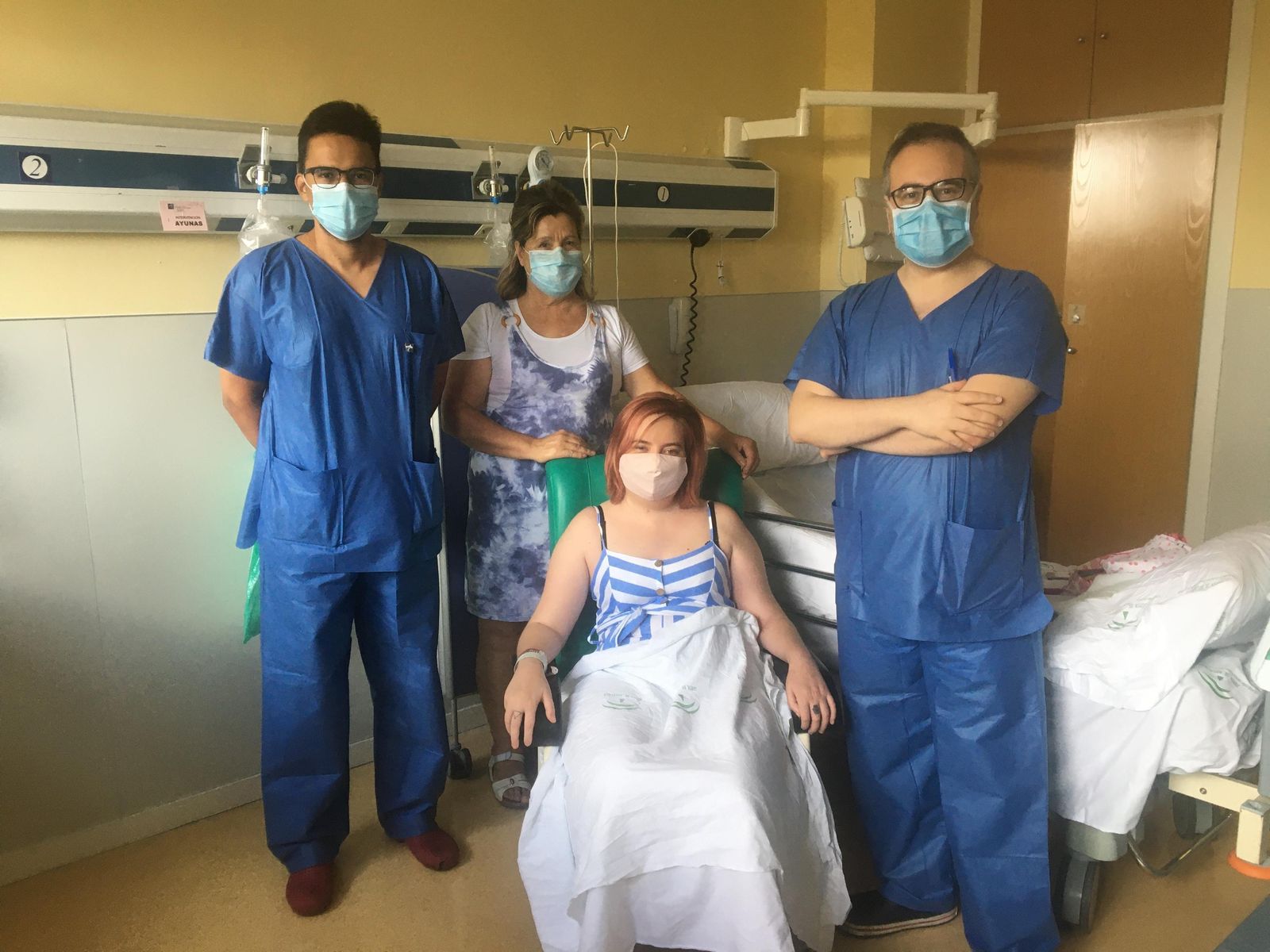La paciente recientemente intervenida junto a un familiar y los dos cirujanos de la sección de vascular del servicio de Neurocirugía del Virgen del Rocío que han realizado la operación.