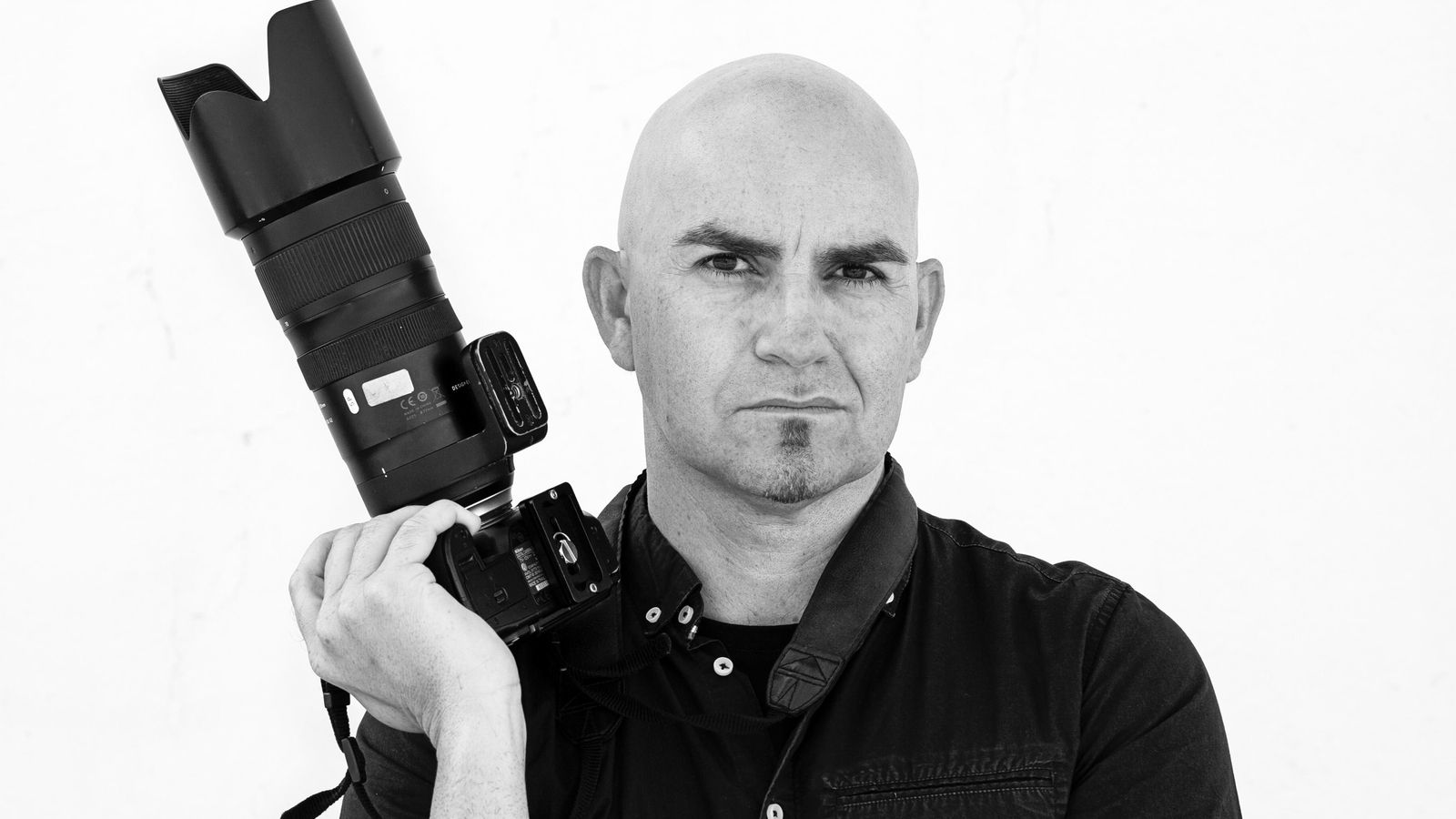 El fotoperiodista Carlos Barba, posando con su instrumento de trabajo