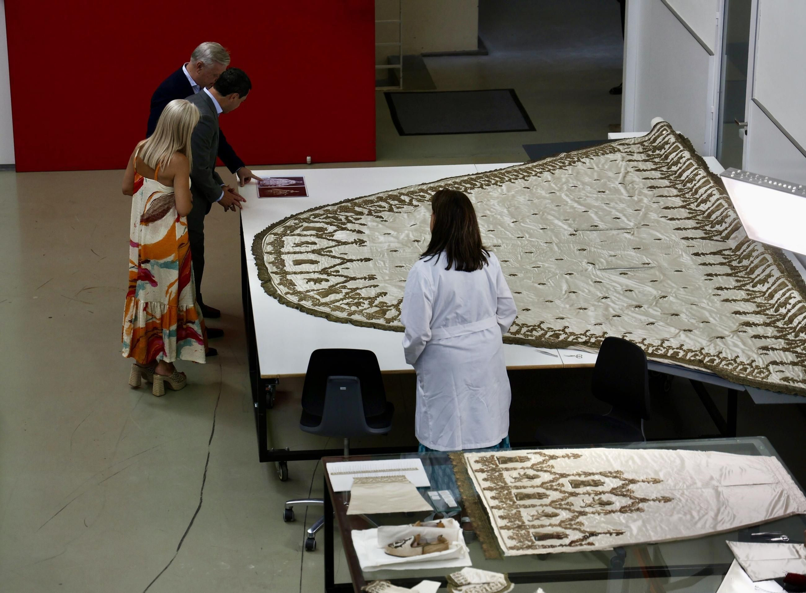 Moreno observa el terno blanco de la Virgen de los Reyes junto a Patricia del Pozo y Juan José Primo.