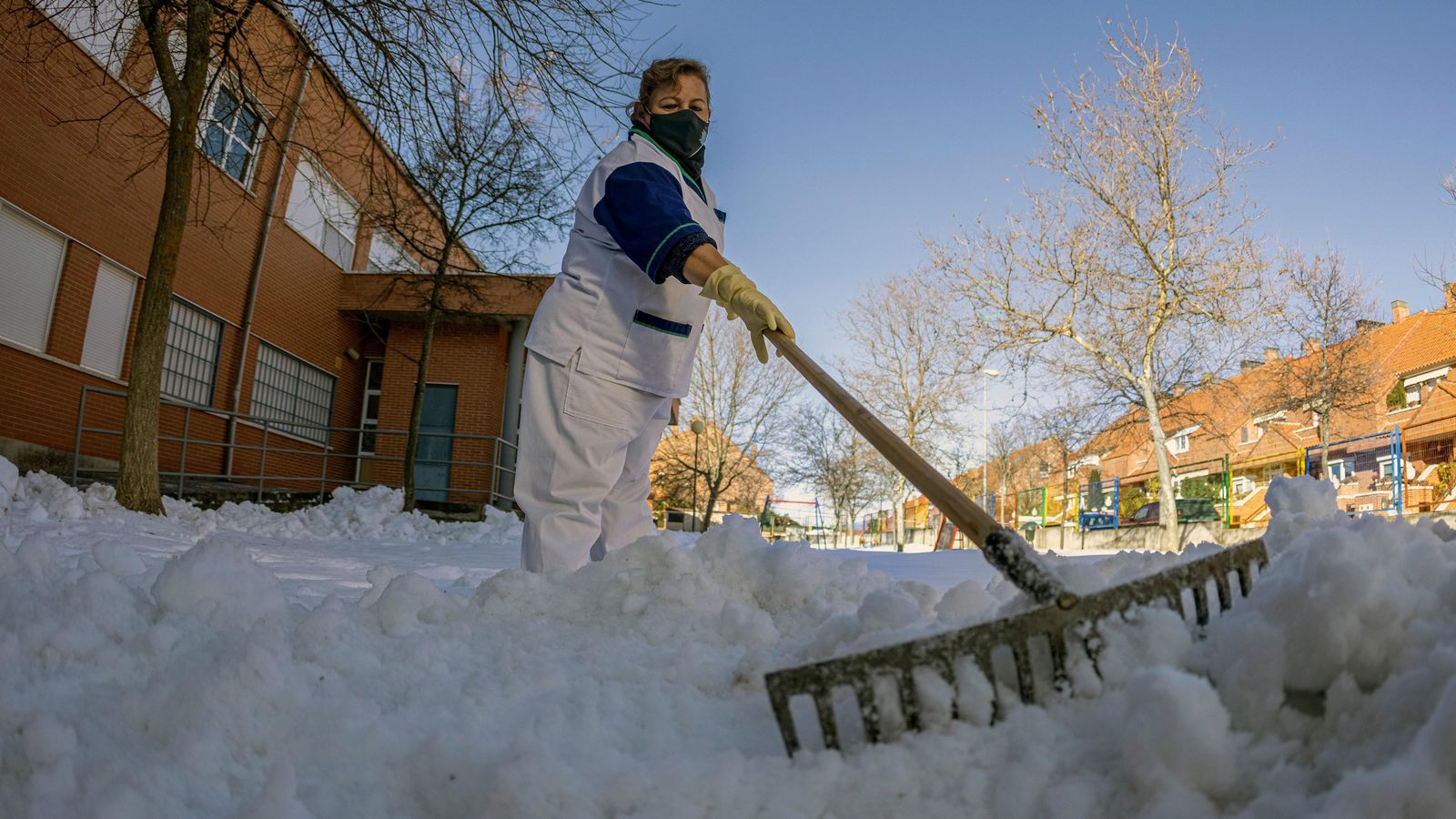 Un trabajadora con el rastrillo, retirando la nieve para evitar el hielo.