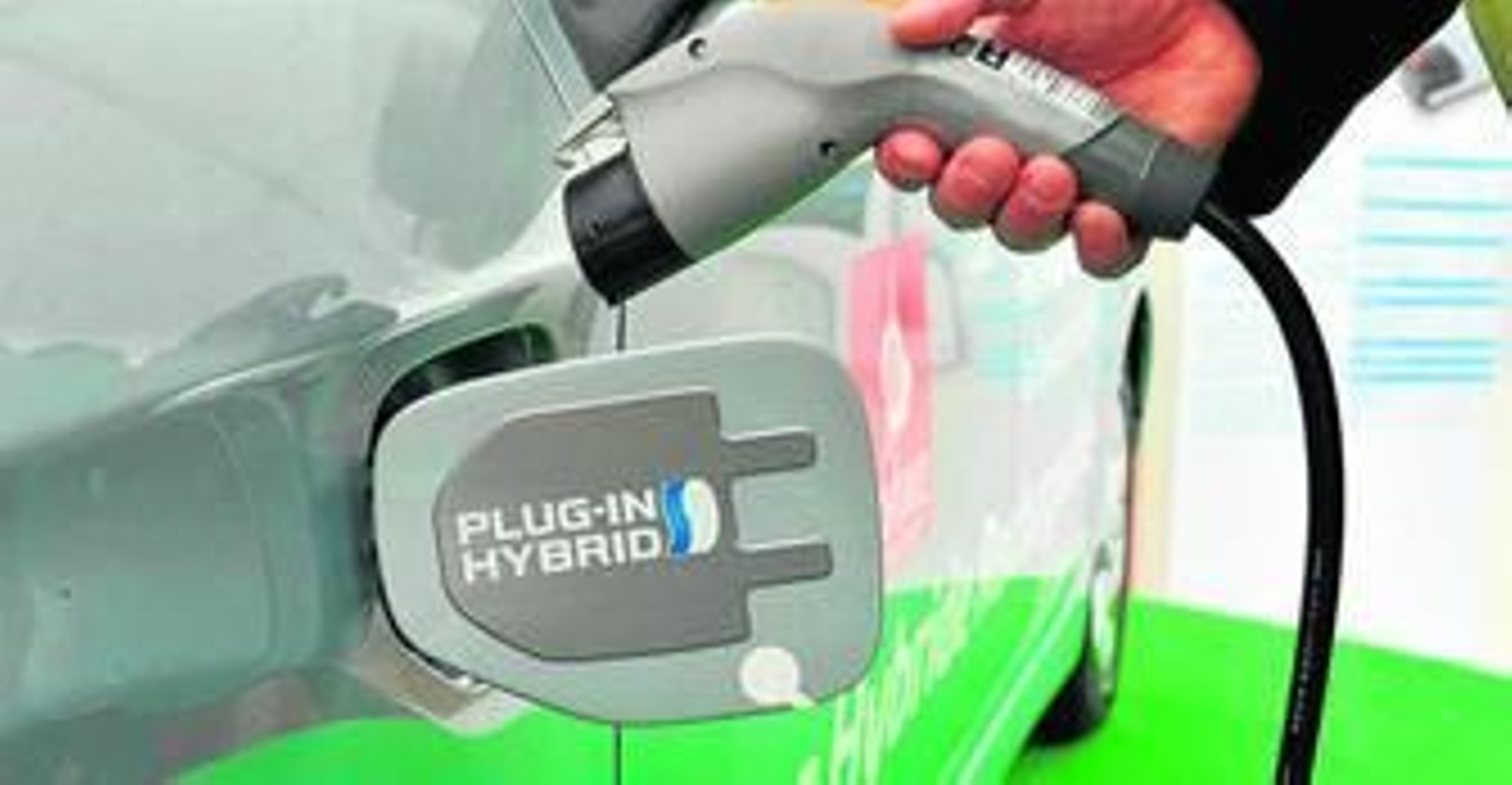 Imagen de un coche híbrido en un punto de recarga.