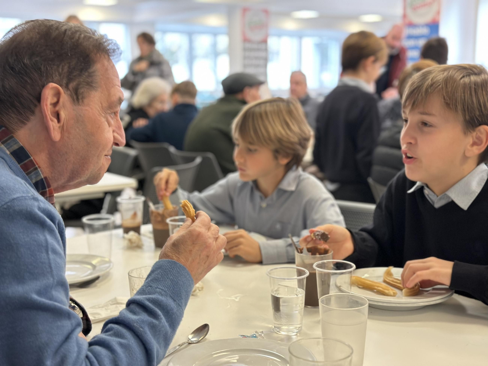Dos alumnos del Colegio Tabladilla meriendan con el usuario de una residencia de ancianos.