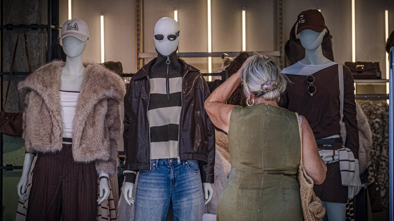 Una mujer observa un escaparate con prendas de abrigo.