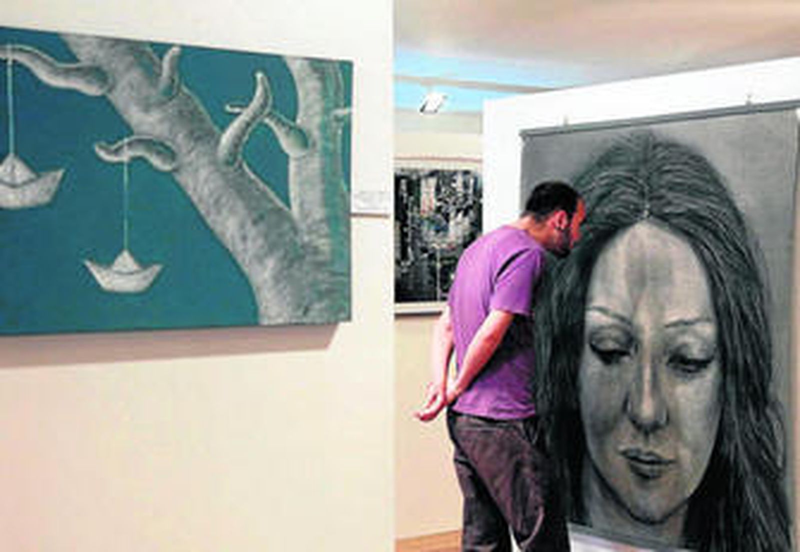 Un visitante mira los detalles de uno de los cuadros en la inauguración.