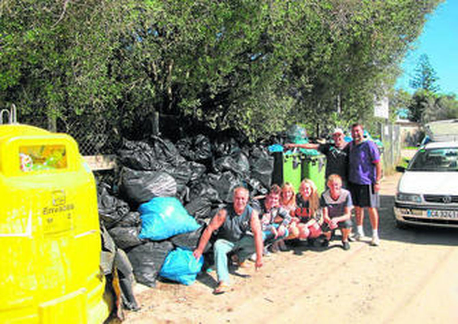Parte del equipo de vecinos que participó en la iniciativa junto con la basura acumulada en los contenedores.