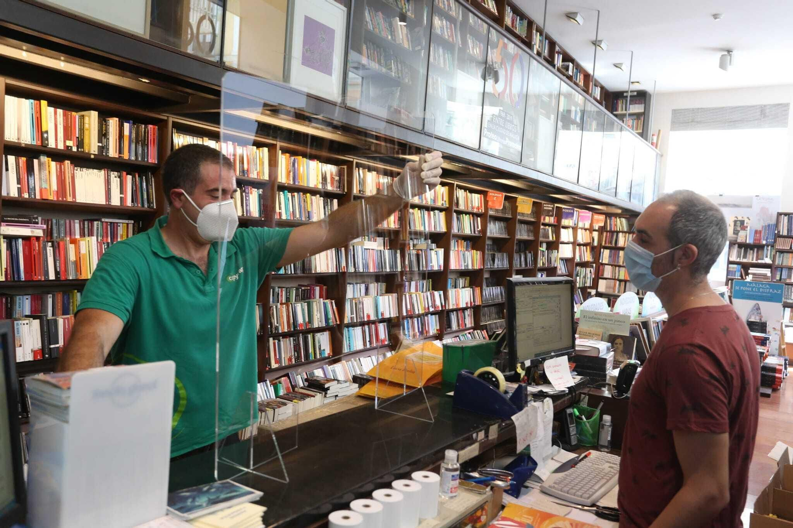 Los responsables de Proteo instalan una mampara en el mostrador de la librería, este lunes.