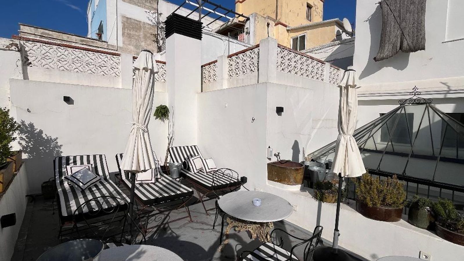 Tumbonas de hierro con veladores de hierro y mármol y tapicería de rayas en la terraza.