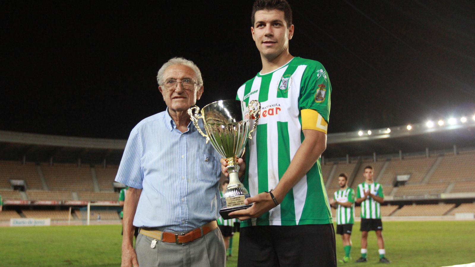 Rafa Verdú entrega la copa de la primera edición a Pelón, capitán del Sanluqueño.