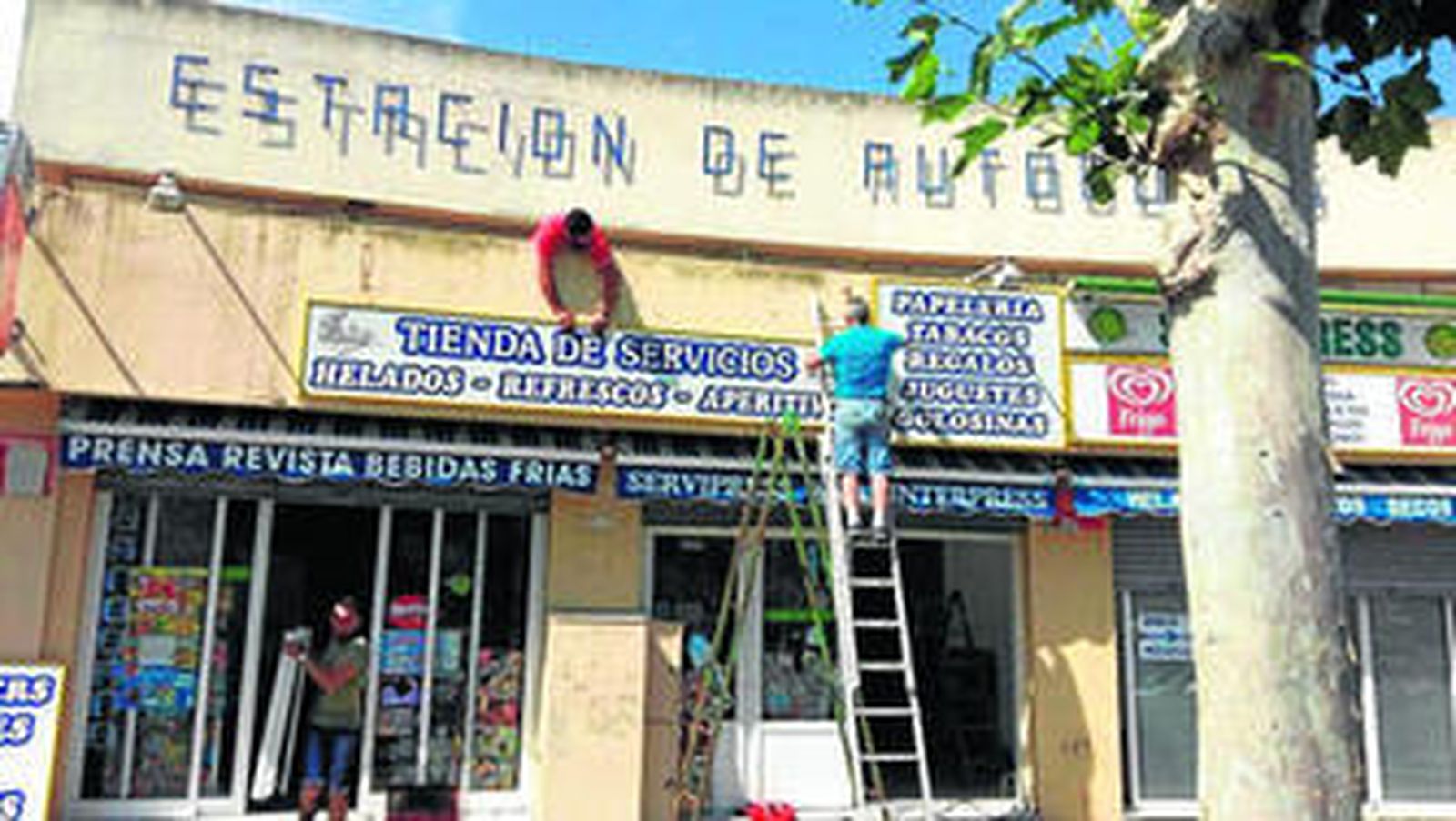 Dos personasl retiran los carteles de la papelería Zaida, ayer.