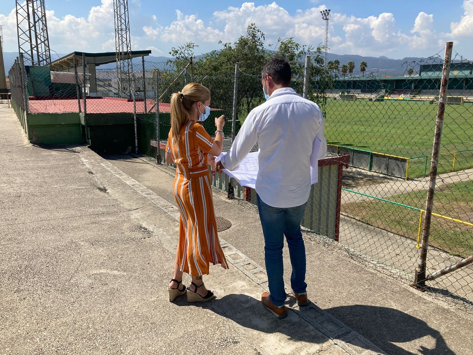 Gallego y García supervisan los planos en el campo de fútbol.