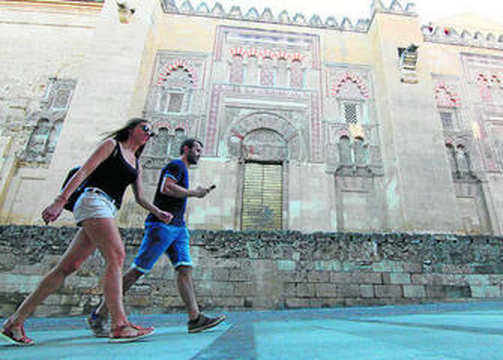 Dos jóvenes pasan ante la puerta de San José de la Mezquita-Catedral de Córdoba.