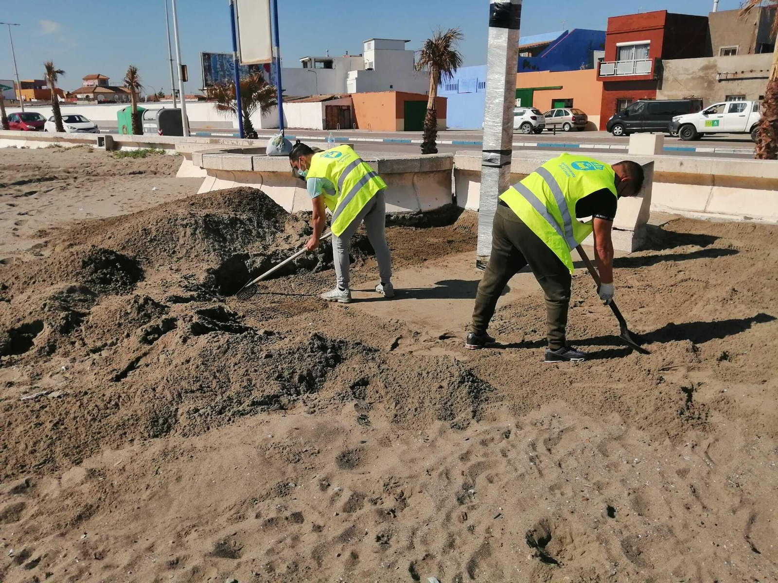 Dos operarios preparan la playa de Levante.