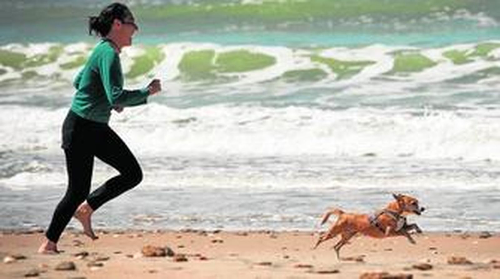 Una mujer juega con su perro ayer en la playa de Camposoto, donde todavía no están colocados los servicios y el uso de la playa es más permisivo.