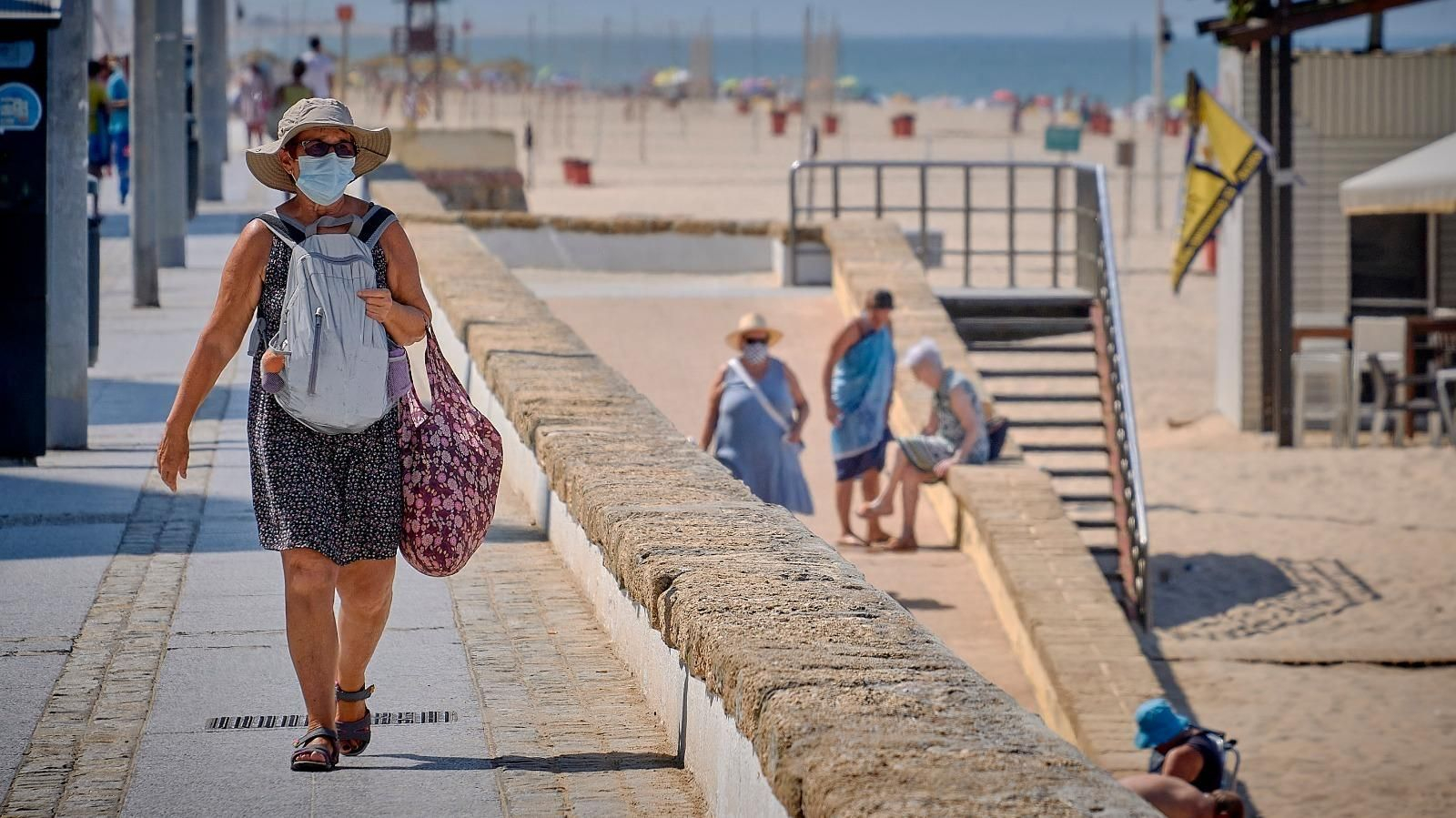 Varias personas llegando a la playa Victoria con la mascarilla puesta.