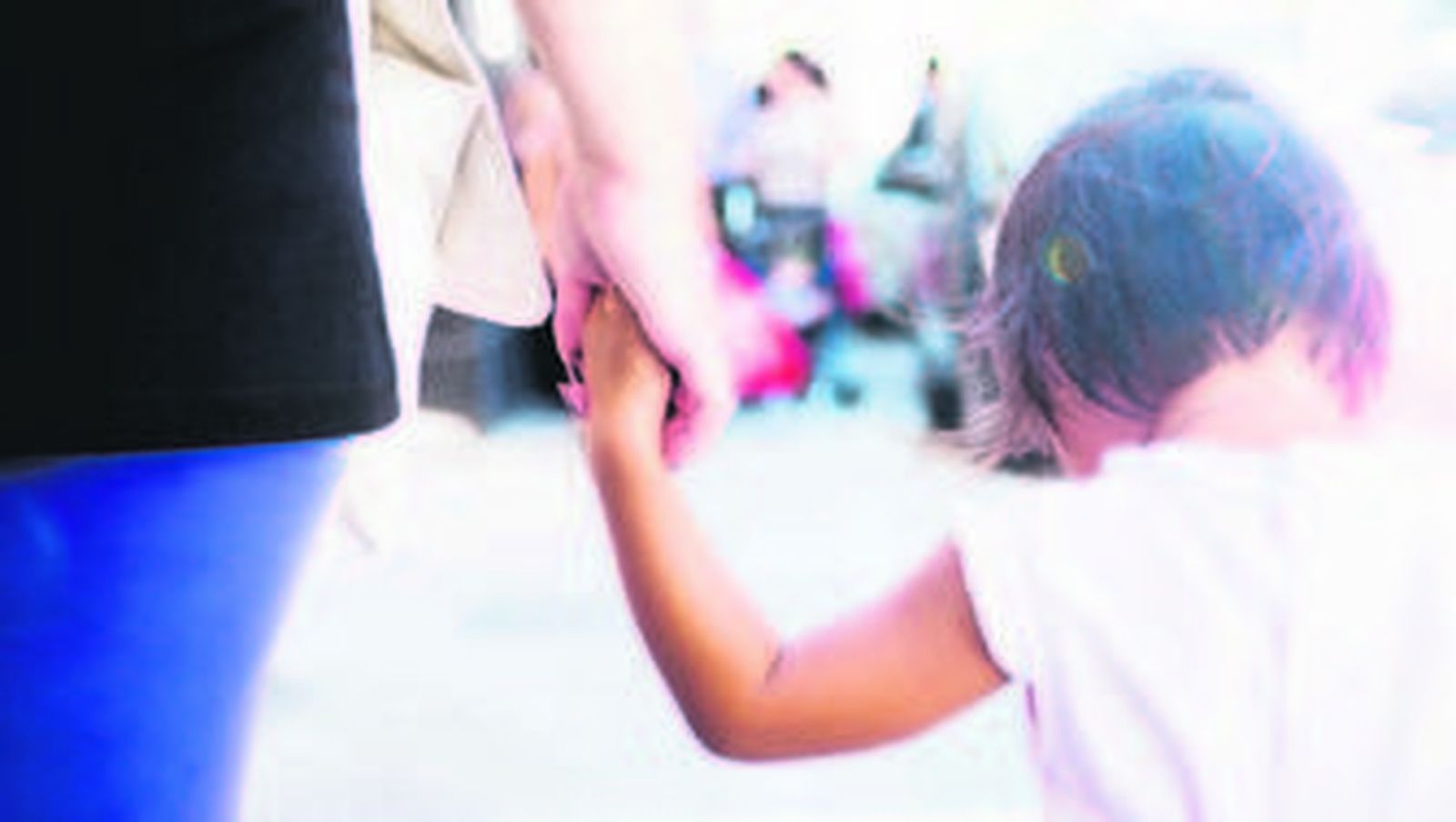 Una madre pasea con su hija de la mano.