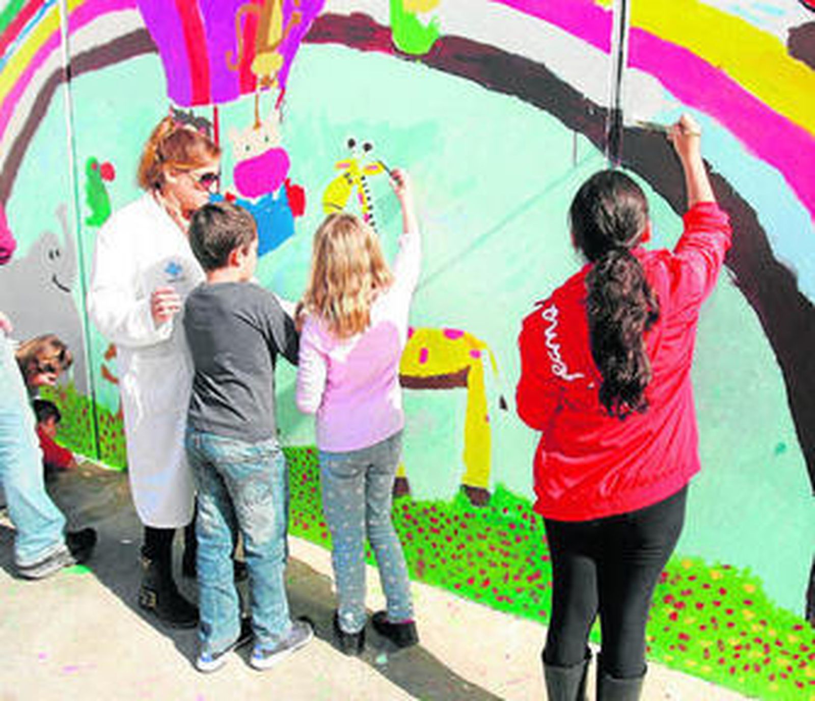 Los niños del Colegio Torrequebrada pintan un mural con la ayuda de una madre.
