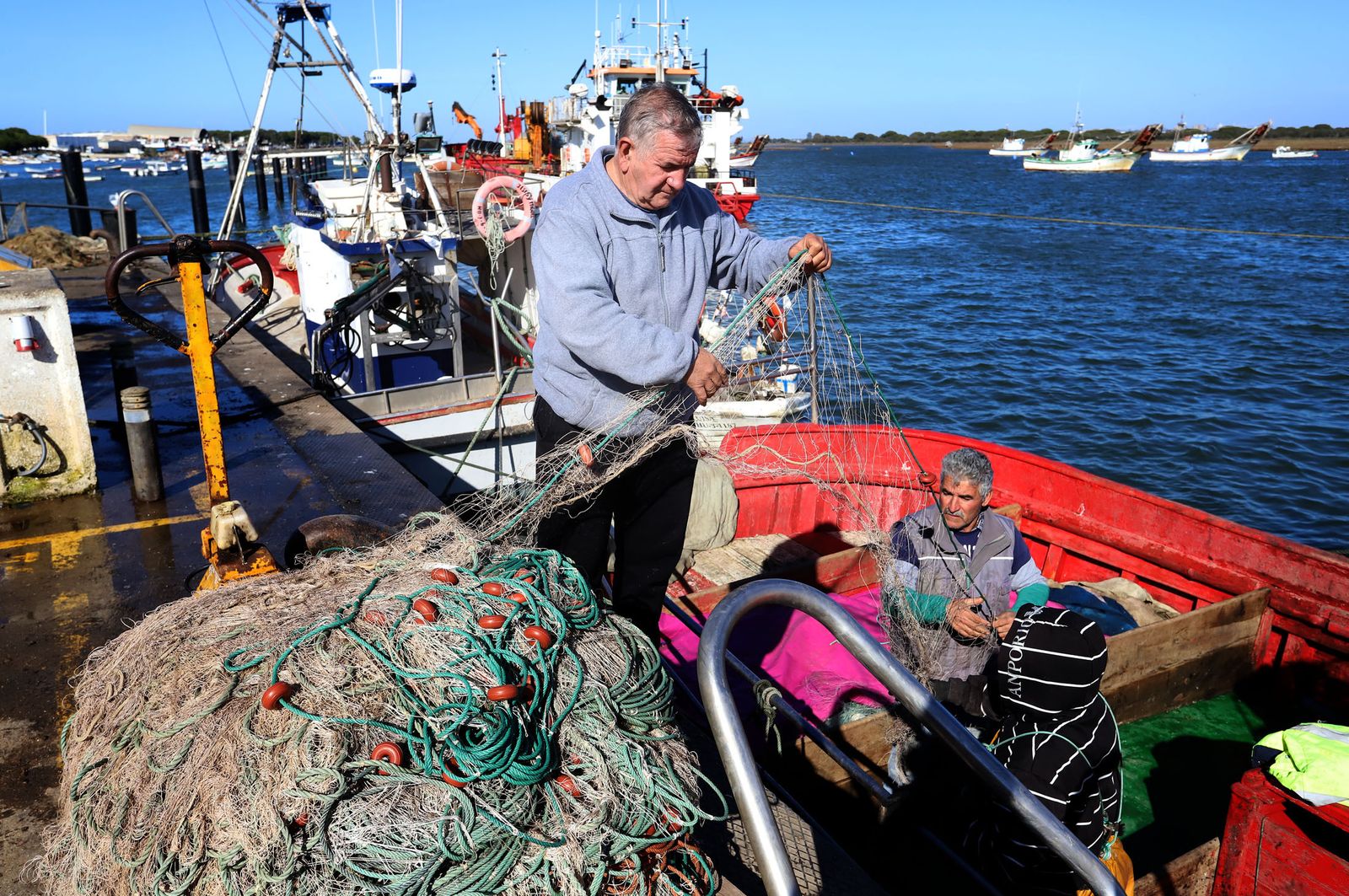 Marineros de Punta Umbria manipulan las redes de pesca.