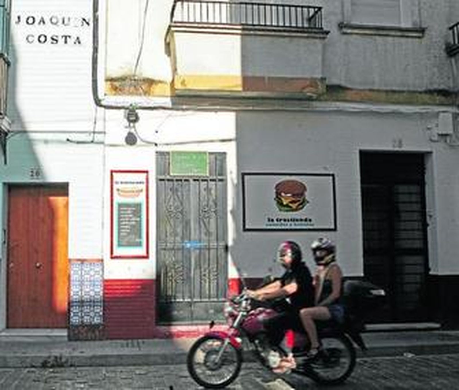 Una motocicleta pasa junto al negocio que regentaba la víctima, Manuel Flores.