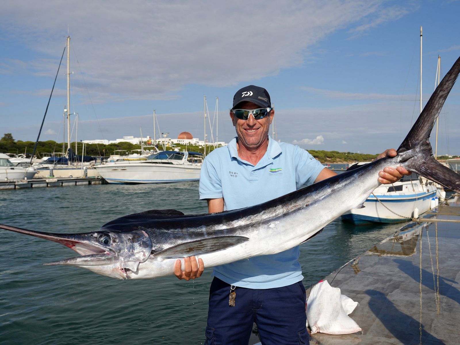 Un miembro del personal de la marina de la ADN Nuevo Portil muestra el marlin blanco de 21 kilos que se hizo con el premio a la mayor pieza