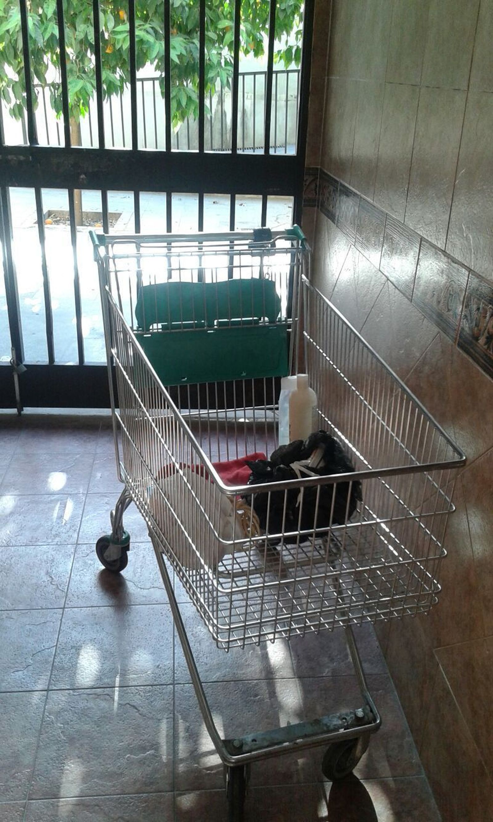 Un carro de la compra dejado por un indigente dentro de un bloque.