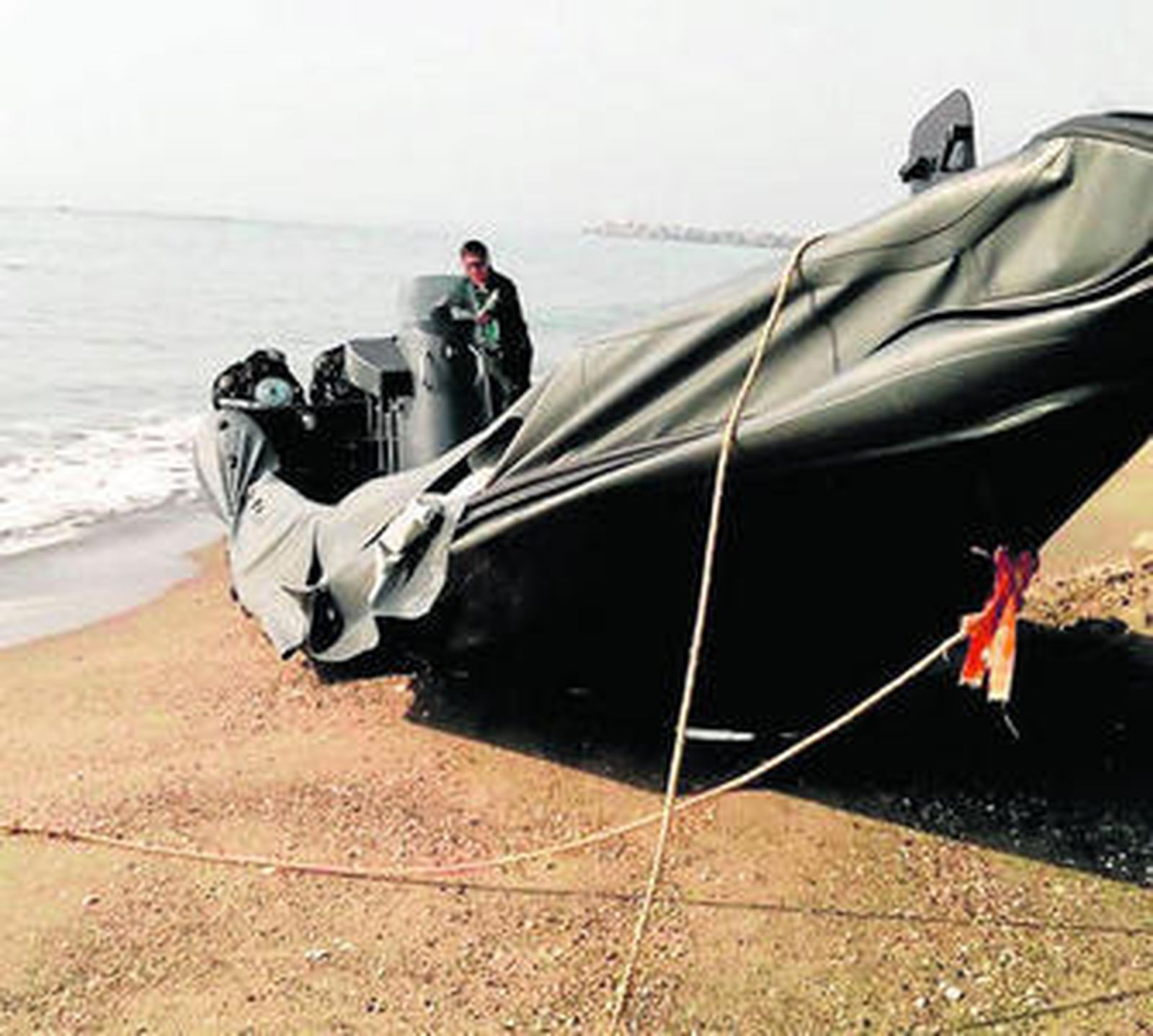 Un agente inspecciona la lancha que fue abandonada en la playa de Sobrevela.