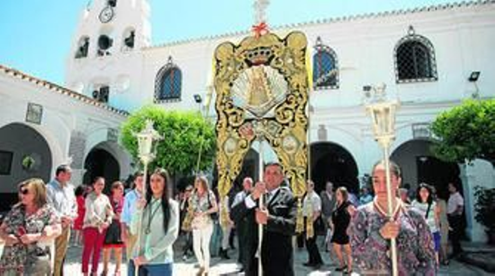 1. El Simpecado de la Hermandad de Emigrantes se dirige al altar del santuario de la Virgen de la Cinta. 2. La misa fue oficiada por el sacerdoteJosé Manuel Barral. 3. La presidenta de la hermandad de la Concha Peregrina; Belén Requena, flanqueada por al subdelegado del Gobierno en Huelva, Enrique Pérez Viguera, y el hermano mayor de La Cinta, Manuel Roméu. 4. Grupo de tamborileros que puso los sones a la ceremonia.