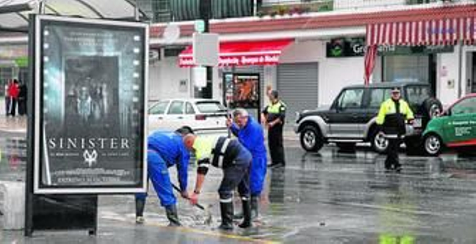Efectivos municipales y de la Policía Local tratan de abrir una alcantarilla en una calle de Cartaya inundada ayer por la lluvia.