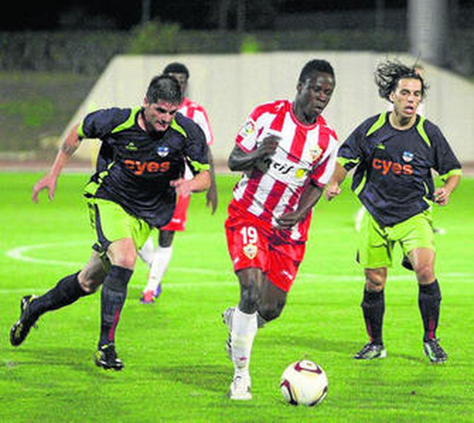 Okoro, que jugó en Roquetas, se lleva el balón ante dos lojeños.