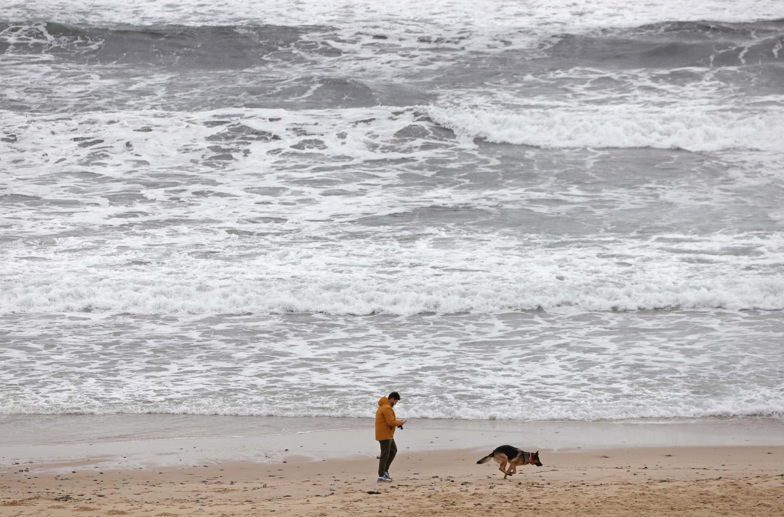 Una persona pasea por Getares junto al mar encrespado.