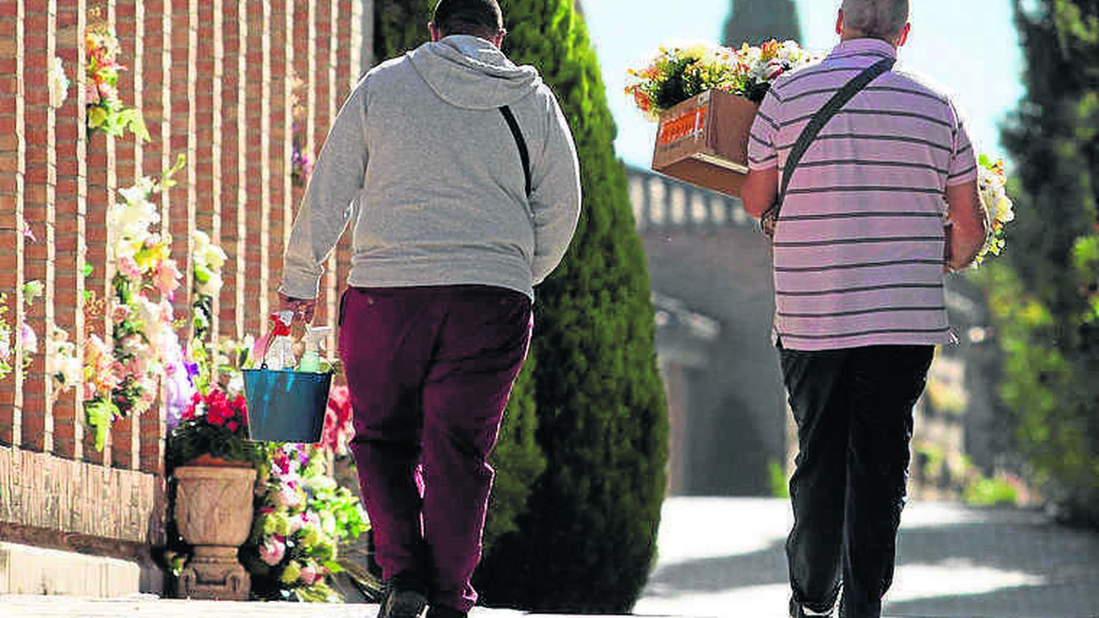 Dos personas pasean por un cementerio en el día de Todos los Santos.