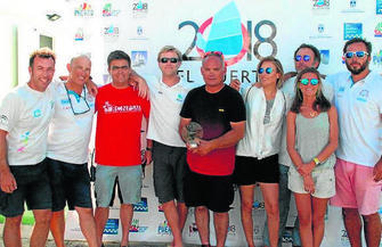 La tripulación del barco vencedor posa con el trofeo conseguido.