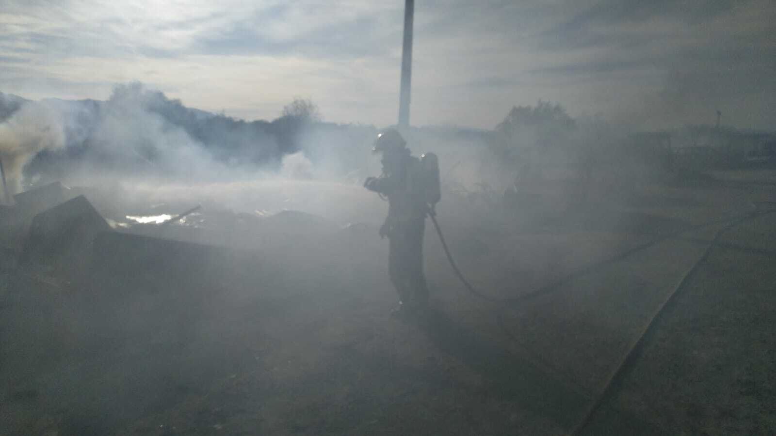 Un bombero entre la nube de humo en el incendio en el aparcamiento de caravanas del polígono Guadalhorce.