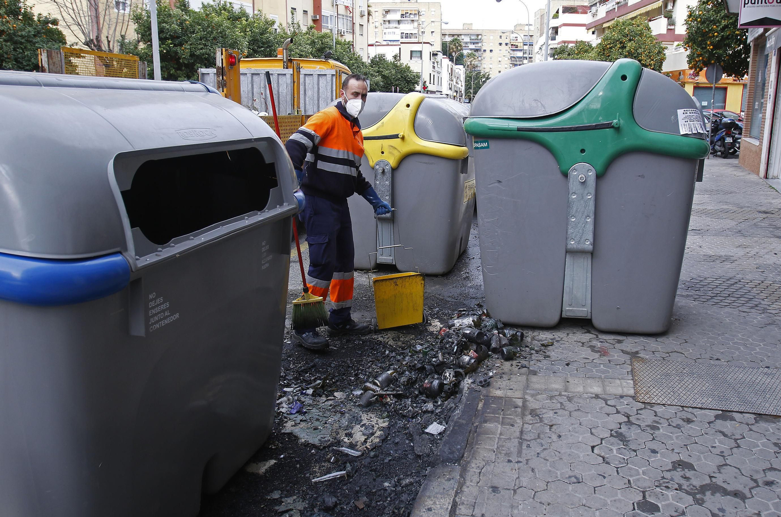 Un empleado de Lipasam recoge restos junto a contenedores de residuos en una calle de la ciudad.